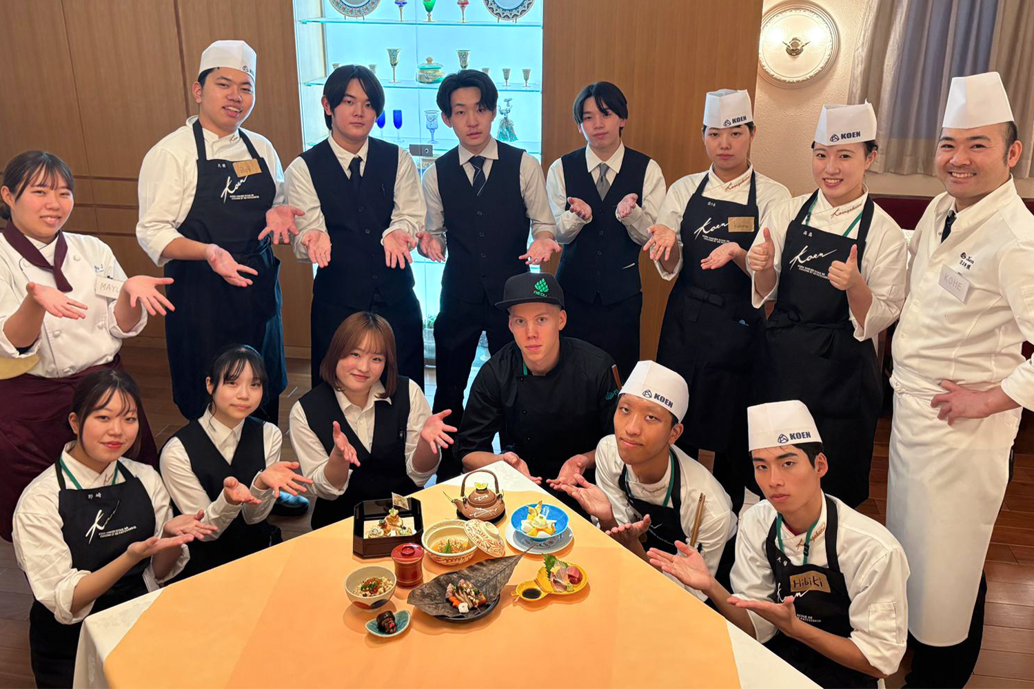 Opiskelijat ovat kerääntyneet esittelemään pöydän ääreen annoksia, jotka ovat tehneet.