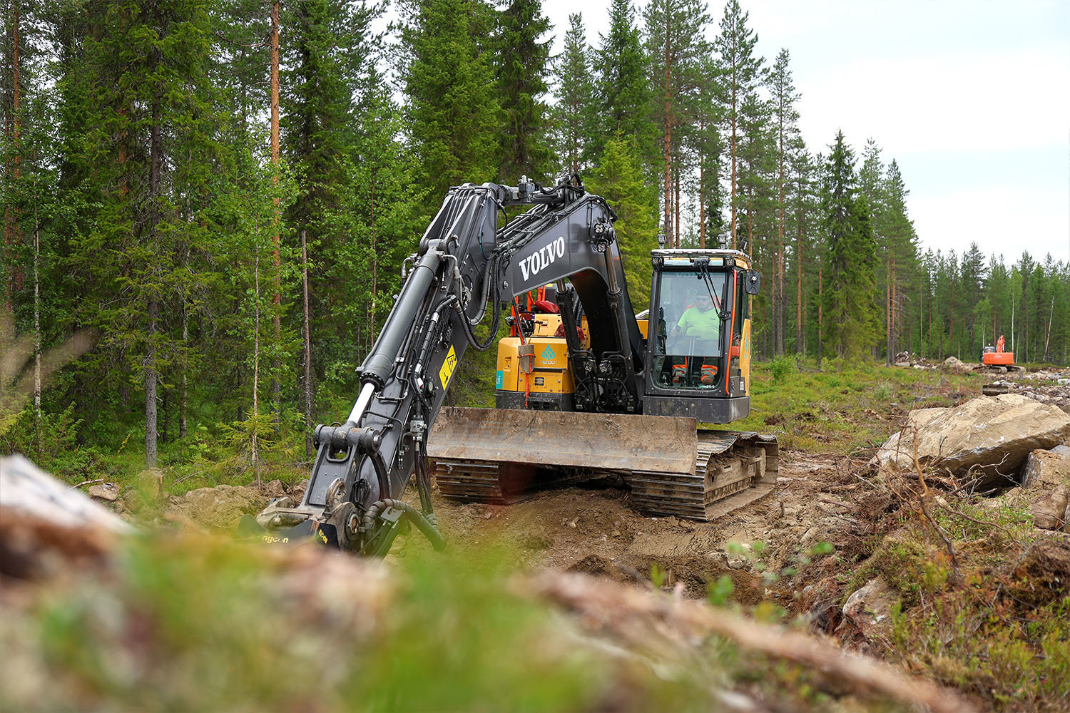 Kaivinkone työskentelee metsäisessä maastossa Tuomijärven ajoharjoitteluradan rakennustyömaalla.